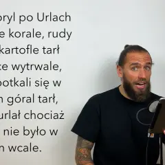 Mężczyzna z brodą i kitką czyta tekst o japońskich łamańcach językowych, gdzie goryl turlał się po Urlach, a góral tarł kartofle.