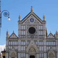 Fasada katedry Santa Maria del Fiore we Florencji, ozdobiona mozaikami i rzeźbami, lśni w słońcu.