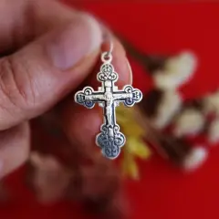 Srebrny krzyż prawosławny w dłoni. Różnice między prawosławiem a katolicyzmem mogą być widoczne w symbolice.