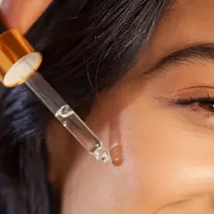 Kropla serum z pipetki zbliża się do twarzy, obiecując widoczne retinol efekty.