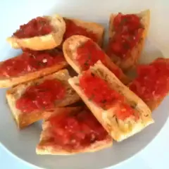 Des tranches de pain grillé garnies de tomates fraîches et d'herbes. Un délice simple et savoureux, parfait pour un apéritif.