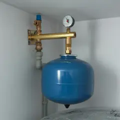 Naczynie przeponowe zamontowane na ścianie, z manometrem i zaworem. Idealne miejsce do instalacji w systemach grzewczych.
