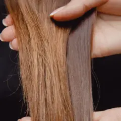 Hände halten zwei Strähnen Haar, eine glänzend, die andere matt und glanzlos.