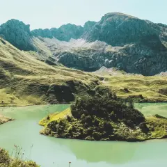 A serene lake reflects the rugged peaks of the Bavarian Forest. Perfect for **wandern im Bayerischen Wald**, this landscape offers a peaceful escape.