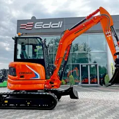 Pomarańczowa koparka gąsienicowa CDM 6035 przed budynkiem z logo Eddi.