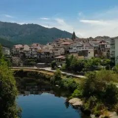 Un pueblo con tejados rojos y casas blancas se alza sobre un río tranquilo. Un lugar perfecto para descubrir qué ver en Ribadavia.
