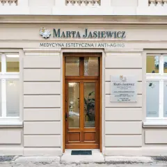 Elegancka fasada gabinetu medycyny estetycznej "Marta Jasiewicz" z drewnianymi drzwiami i oknami.