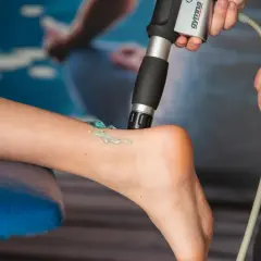 Terapia falą uderzeniową: aplikator z żelem na łydce pacjenta, przygotowanie do zabiegu.