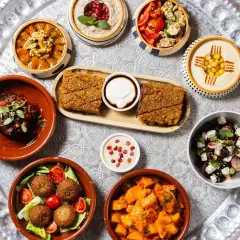 Un vassoio con diverse pietanze mediorientali, perfetto per scoprire dove mangiare a Milano. Hummus, falafel, insalate e spezzatini invitano a un viaggio di sapori.