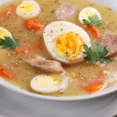 Pyszna zupa na Wielkanoc z jajkami przepiórczymi, kiełbasą i marchewką, doprawiona ziołami.
