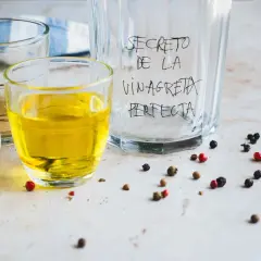 Ingredientes para la receta de vinagreta perfecta: aceite, vinagre y granos de pimienta.