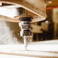 Precyzyjny frez CNC w akcji, tworzący drobny pył podczas obróbki drewna.