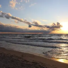 Zachód słońca nad Bałtykiem, złote fale obmywają piaszczystą plażę. Idealne miejsce na kąpielisko na mierzei helskiej.