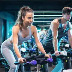 Para ćwiczy na rowerach stacjonarnych. Intensywny trening spinningowy w klubie fitness.