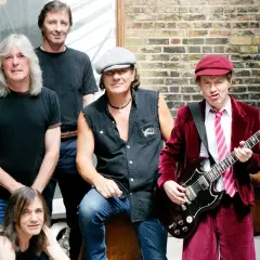 Zespół AC/DC w komplecie, gotowy do rock and rolla. Angus Young z gitarą, Brian Johnson w kultowym stroju.