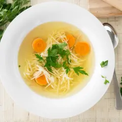 Aromaticzny rosół z makaronem i marchewką, ozdobiony natką pietruszki. To może być najstarszy przepis na rosół, który rozgrzewa serce.