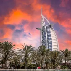 Zachód słońca nad Dubajem, palmy i hotel Burdż al-Arab. Zastanawiasz się, ile kosztuje wycieczka do Dubaju?