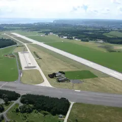 Lotnisko w Gdyni z lotu ptaka. Widać pasy startowe, trawiaste tereny i budynki.