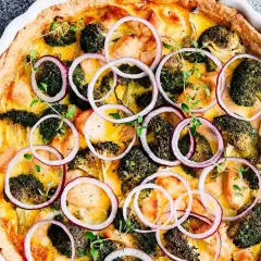 En gyllene vegansk paj med broccoli, kycklingbitar och rödlök, toppad med färska örter.
