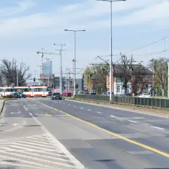 Ulica z tramwajem, samochodami i budynkami w tle.