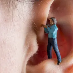 Kleine Figur im Ohr, die versucht, den Tinnitus zu bekämpfen. Vitamin B12 könnte helfen.