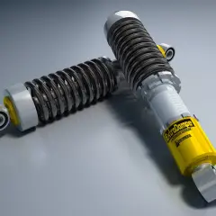 Dos amortiguadores de coche, uno amarillo con la marca "ExtraDampe", esenciales para entender qué son los amortiguadores de un coche.
