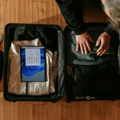 Pakowanie bagażu podręcznego: ubrania, buty i tablet do walizki.