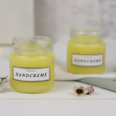 Zwei Gläser mit selbstgemachter Handcreme, verziert mit kleinen Blüten. Perfekt zum Handcreme selber machen für Kinder.