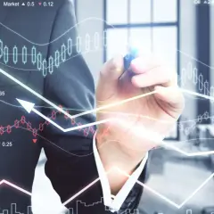 Biznesmen rysuje wykresy giełdowe i analizuje dane finansowe.