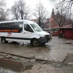 Biały bus Kik-Bus z napisem "OLKUSZ-SOSNOWIEC-KATOWICE" na mokrym placu przed budynkiem dworca.