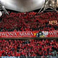Tłum kibiców Widzewa w czerwonych barwach, z transparentem "Czerwona Armia Widzewa".