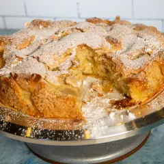 Pyszne, domowe ciasto z jabłkami, posypane cukrem pudrem, czeka na spróbowanie.
