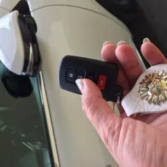 Uszkodzony transponder w kluczyku objawy: auto nie odpala, miga kontrolka. Dłoń trzyma kluczyk z breloczkiem w kształcie słońca.