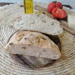 Pan rústico con aceitunas, tomates, queso y aceite de oliva. Un delicioso pan de aceitunas listo para disfrutar.