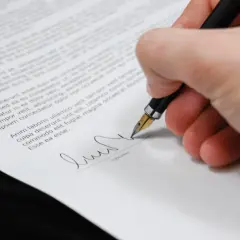 Podpisanie polskiej umowy w Niemczech. Dłoń z piórem podpisuje dokument.