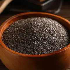 Nasiona chia jak jeść? W drewnianej misce pełnej drobnych, czarnych ziarenek. Idealne do dodania do jogurtu, owsianki czy smoothie.