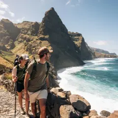 Couple en randonnée sur le sentier escarpé de **Randonnée Cap Vert**, dominant l'océan turquoise et les falaises spectaculaires.