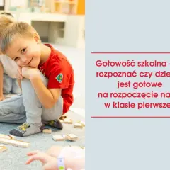 Uśmiechnięty chłopiec w czerwonej koszulce bawi się klockami z innymi dziećmi.
