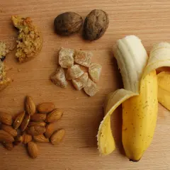 Ciastko, banan, migdały i kandyzowany imbir – wszystko, co ma dużo węglowodanów, na drewnianym blacie.