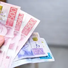 Dłoń trzyma szwedzkie korony. Czy w Szwecji można płacić euro? Nie, używa się tam własnej waluty.