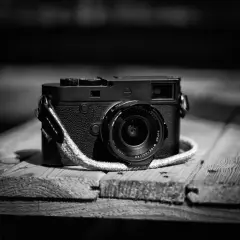 Klasyczny aparat Leica M10 Monochrom z obiektywem na drewnianym blacie.