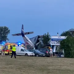 Wypadek na lotnisku Chrcynno. Rozbity samolot, wozy strażackie, karetki i policja na miejscu zdarzenia.
