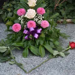 Piękna wiązanka z różowych i białych róż, ozdobiona fioletową wstążką. Dodatki do wiązanek na cmentarz, które dodają uroku i pamięci.