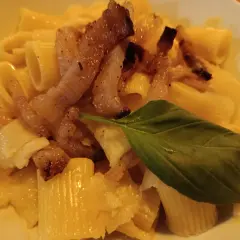 Makaron z chrupiącym guanciale, parmezanem i listkiem bazylii. To właśnie guanciale nadaje daniu wyjątkowy smak.