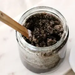 Słoik z domowym peelingiem z kawy, gotowy do użycia. Drewniana łyżeczka zanurzona w bogatej mieszance.