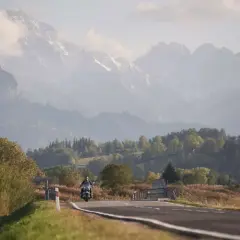 Motocyklista na drodze w górach, jesienny krajobraz.