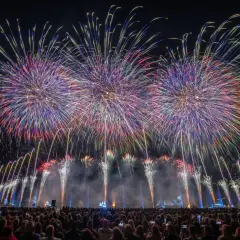 Spectacle pyrotechnique grandiose pour la fete du lac, illuminant le ciel nocturne de gerbes multicolores au-dessus d'une foule admirative.