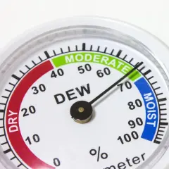 Un higrómetro que mide la humedad del aire, con zonas indicadas como "DRY", "MODERATE" y "MOIST".