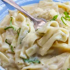 Pyszny makaron z tuńczykiem w sosie śmietanowo-serowym, udekorowany świeżą bazylią i parmezanem. Idealny na szybki obiad.
