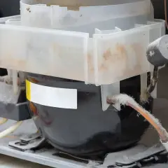 Composants d'un congélateur Liebherr, poussière accumulée sur le compresseur et les tuyaux, possible problème température congélateur liebherr.